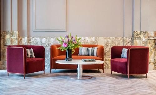 2 Stühle und ein Tisch mit einer Blumenvase in der Unterkunft DoubleTree By Hilton Brussels City in Brüssel