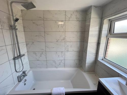 a white bathroom with a tub and a sink at The Quiet Sanctuary - 4 Bedroom in Swindon