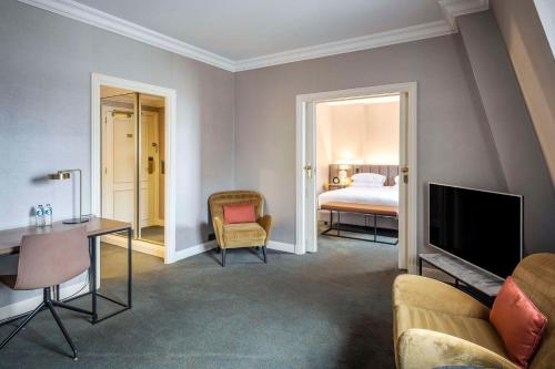 a living room with a bed and a tv and a bedroom at Hilton Brussels Grand Place in Brussels