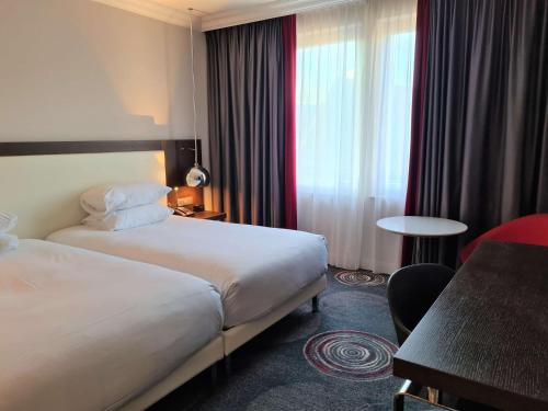 a hotel room with two beds and a table at Hilton Brussels Grand Place in Brussels