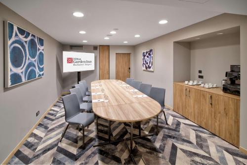 a conference room with a wooden table and chairs at Hilton Garden Inn Bucharest Airport in Otopeni