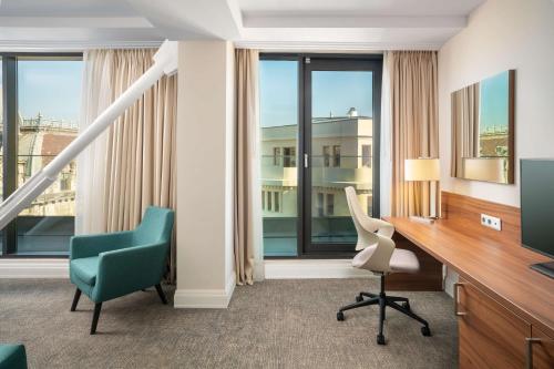 a room with a desk and two chairs and a television at Hilton Garden Inn Bucharest Old Town in Bucharest