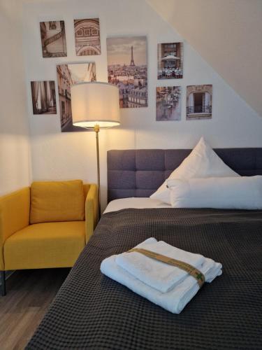 a hotel room with a bed and a yellow chair at Modern-Living Stadt-Appartement Mitte in Bielefeld