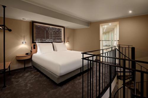 um quarto com uma cama branca e uma escada em Wasserturm Hotel Cologne, Curio Collection by Hilton em Colônia