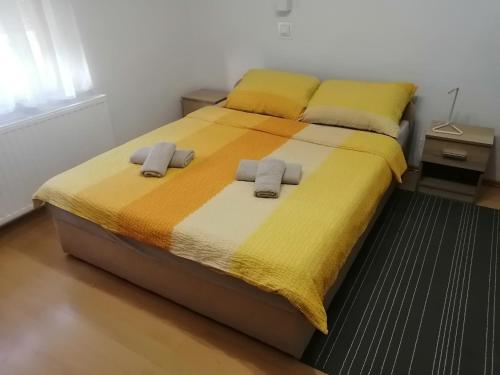 um quarto com uma cama grande com lençóis amarelos e laranja em Soba LIPA em Valpovo