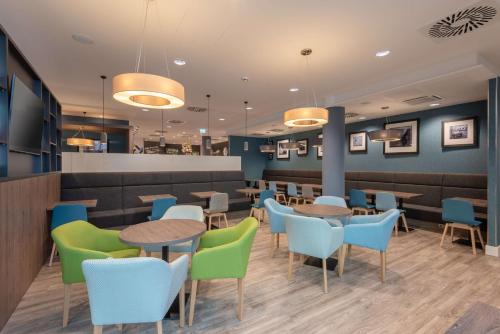 a restaurant with blue and green chairs and tables at Hampton by Hilton Düsseldorf City Centre in Düsseldorf