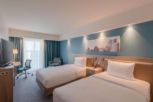 a hotel room with two beds and a television at Hampton by Hilton Düsseldorf City Centre in Düsseldorf
