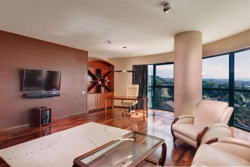 a living room with a tv and a table and chairs at DoubleTree by Hilton Hotel Cluj - City Plaza in Cluj-Napoca
