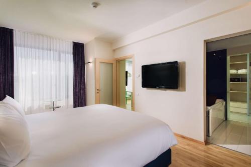 a bedroom with a white bed and a flat screen tv at DoubleTree by Hilton Hotel Cluj - City Plaza in Cluj-Napoca
