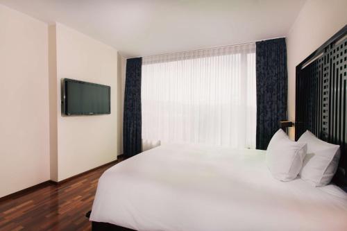 a bedroom with a large white bed and a tv at DoubleTree by Hilton Hotel Cluj - City Plaza in Cluj-Napoca