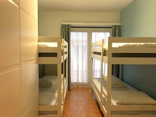 une chambre avec trois lits superposés et une fenêtre dans l'établissement Vakantieappartement "The Seagull" vlakbij het strand, à Nieuport