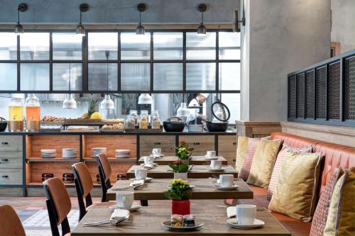 a restaurant with wooden tables and chairs and a kitchen at DoubleTree By Hilton Rome Monti in Rome