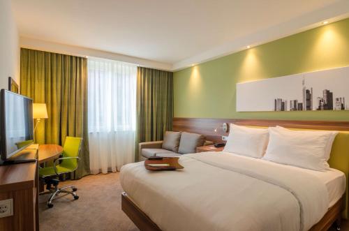 a hotel room with a large bed and a desk at Hampton by Hilton Frankfurt City Centre in Frankfurt