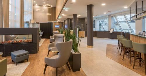 a lobby with a bar and chairs and a fireplace at Hilton Garden Inn Frankfurt City Centre in Frankfurt/Main