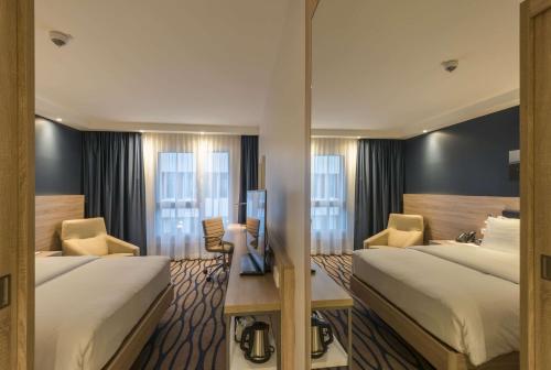 a hotel room with two beds and a television at Hampton By Hilton Frankfurt Airport in Frankfurt/Main