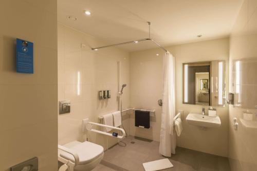 a white bathroom with a toilet and a sink at Hampton By Hilton Frankfurt Airport in Frankfurt