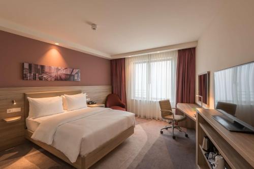 a hotel room with a bed and a desk and a television at Hampton By Hilton Frankfurt City Centre East in Frankfurt