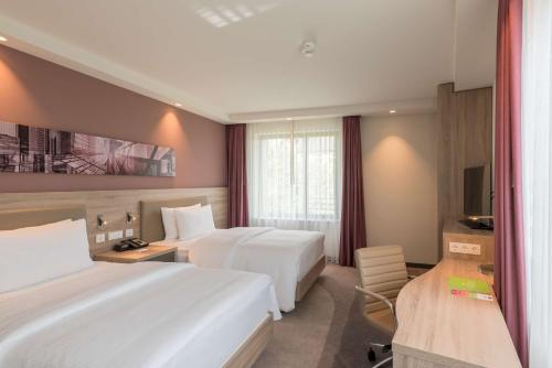 a hotel room with two beds and a television at Hampton By Hilton Frankfurt City Centre East in Frankfurt
