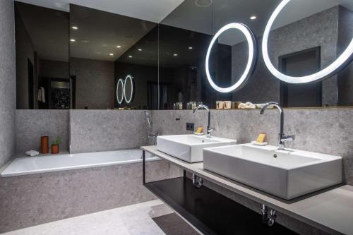 een badkamer met 2 wastafels, een bad en spiegels bij Hilton Garden Inn Mannheim in Mannheim