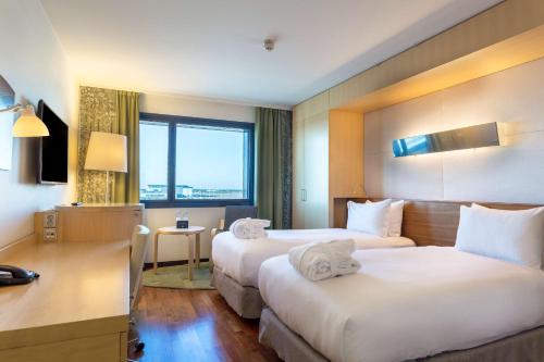ein Hotelzimmer mit 2 Betten und einem Schreibtisch in der Unterkunft Hilton Helsinki Airport in Vantaa