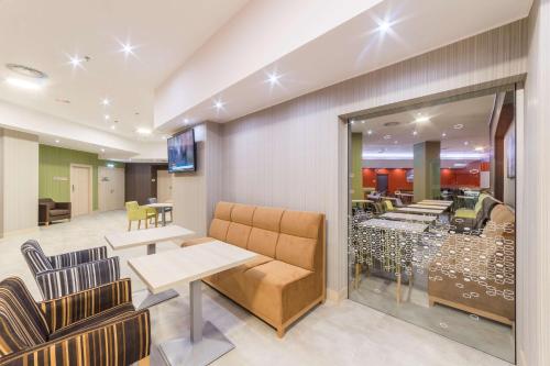 a waiting room with chairs and a table and a restaurant at Hampton By Hilton Iasi in Iaşi