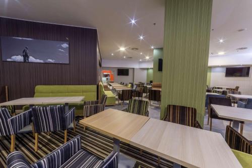 a restaurant with tables and chairs and a tv on the wall at Hampton By Hilton Iasi in Iaşi