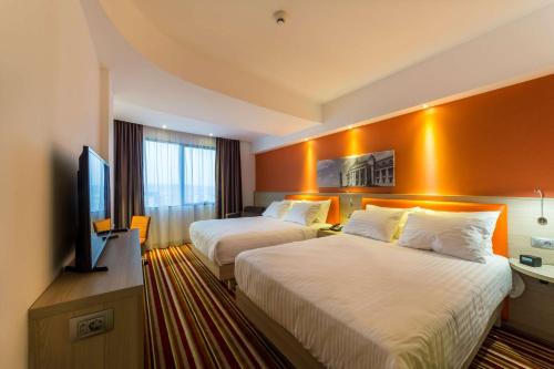 a hotel room with two beds and a flat screen tv at Hampton By Hilton Iasi in Iaşi