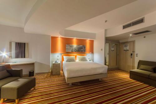ヤシにあるHampton By Hilton Iasiのベッドルーム1室(ベッド1台、ソファ、椅子付)