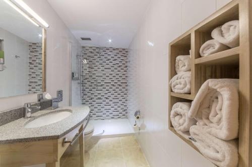 a bathroom with a sink and a shower with towels at Hampton By Hilton Iasi in Iaşi