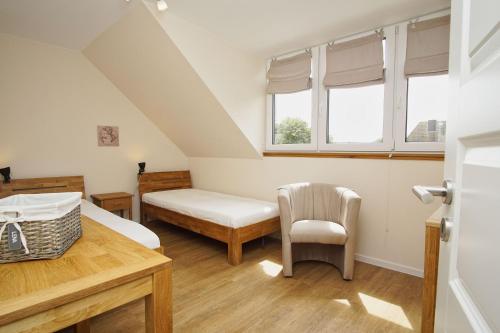 a bedroom with a bed and a chair and windows at modernes Ferienhaus mit eigener Terrasse und kleinem Garten - Ferienhaus Liva in Dranske