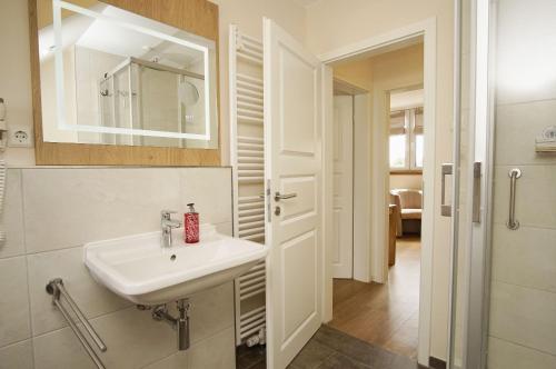 a white bathroom with a sink and a mirror at modernes Ferienhaus mit eigener Terrasse und kleinem Garten - Ferienhaus Liva in Dranske
