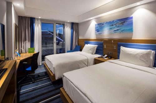 イスタンブールにあるHampton by Hilton Istanbul Kurtkoyのベッド2台とデスクが備わるホテルルームです。