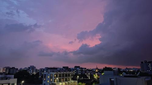 a city skyline with a cloudy sky at sunset at AMBIENT HOME STAY, In Nashik in Nashik