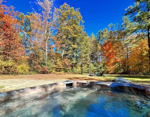 a pond in the middle of a park with trees at Ski Chalet 6 min to Sunday River - Hot Tub, Home Theater, Game Room, Fire Pit - Sleeps 12 in Bethel