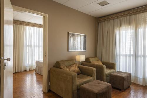 - un salon avec un canapé, des chaises et des fenêtres dans l'établissement Monreale Express Ribeirão Preto, à Ribeirão Preto