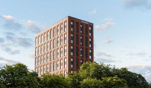 a tall brown building with trees in front of it at Hampton By Hilton Kiel in Kiel