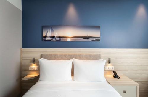 a hotel room with a bed with white pillows at Hampton By Hilton Kiel in Kiel