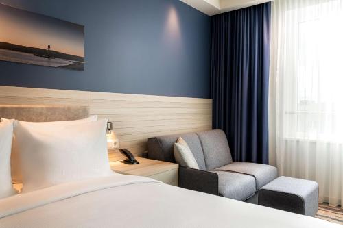 a hotel room with a bed and a chair at Hampton By Hilton Kiel in Kiel