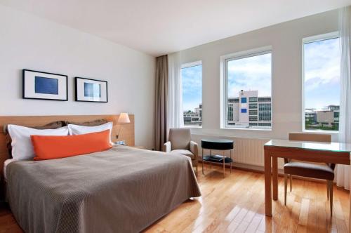 Habitación de hotel con cama, escritorio y ventanas en Hilton Reykjavik Nordica, en Reikiavik