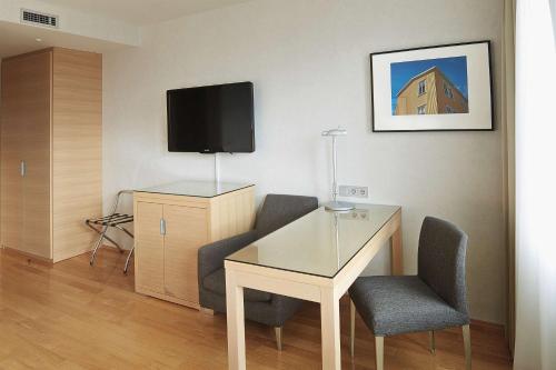 a room with a desk and two chairs and a tv at Hilton Reykjavik Nordica in Reykjavík
