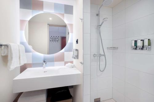 a white bathroom with a sink and a shower at Hampton By Hilton Kaiserslautern in Kaiserslautern