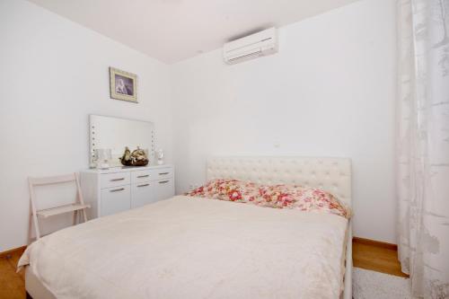 a white bedroom with a bed and a dresser at Tatiana Penthouse in Podstrana