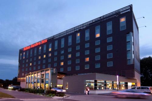 a hotel building with a woman standing in front of it at Hilton Garden Inn Krakow in Kraków