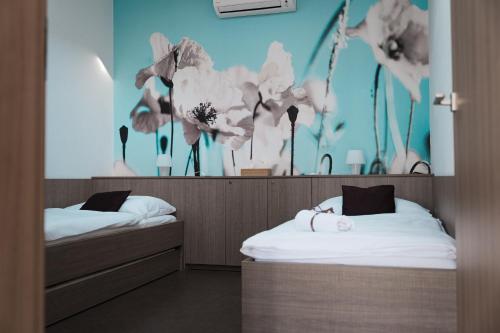 2 camas en una habitación con flores en la pared en Penzion u Hošků, en Vrbice
