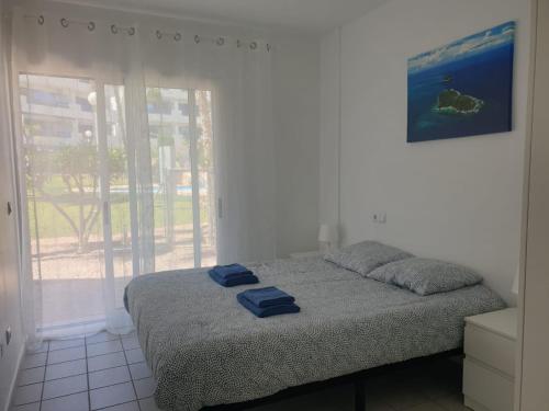 una camera da letto con un letto con due asciugamani blu sopra di La Calma - one bedroom apartment by the pool in Playa Flamenca a Playas de Orihuela