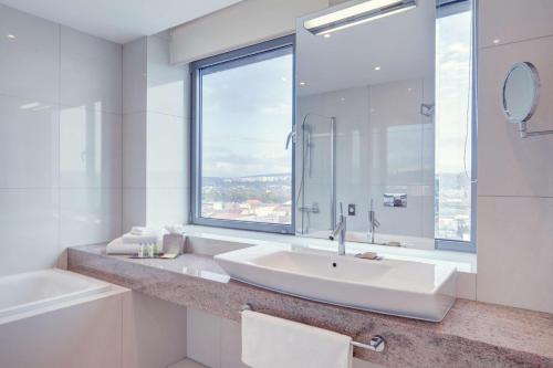 a white bathroom with a sink and a window at DoubleTree By Hilton Košice in Košice