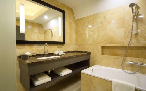 y baño con lavabo, bañera y espejo. en DoubleTree by Hilton Kazan City Center, en Kazán