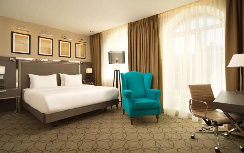 1 dormitorio con 1 cama y 1 silla azul en DoubleTree by Hilton Kazan City Center, en Kazán