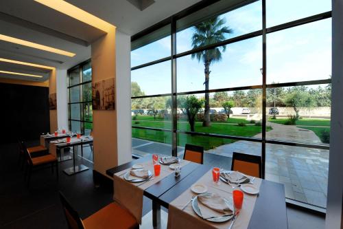 una sala da pranzo con tavoli, sedie e una grande finestra di Hilton Garden Inn Lecce a Lecce