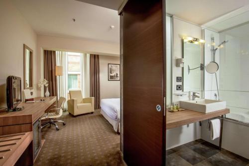 a hotel room with a sink and a bedroom at DoubleTree By Hilton Milan in Milan